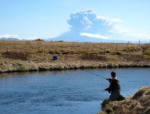 Fly fishing in the kingdom of the volcanoes. Eyjafjallajokull eruption in the background