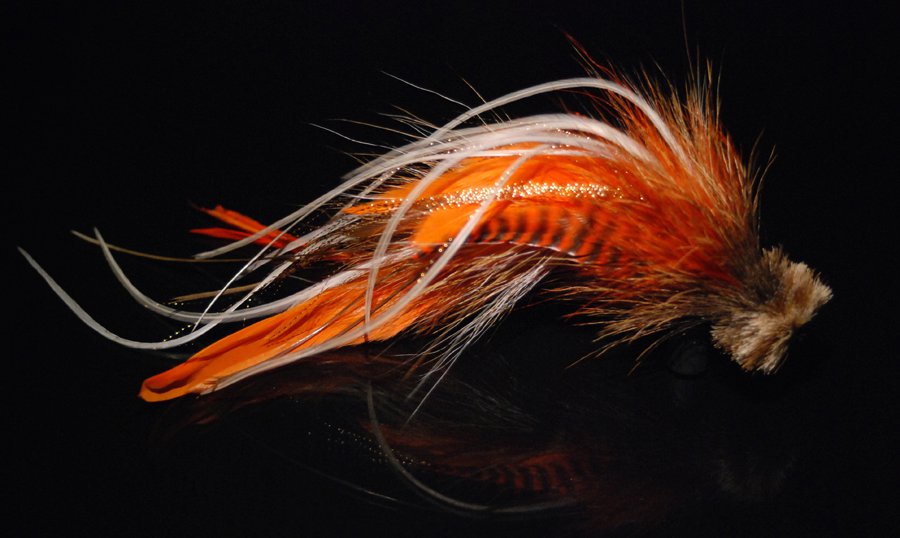This is a combination of brown and orange schlappen mixed with tan bucktail and with  microbarb saddles with a tightly packed tan deer hair head