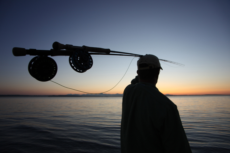 Mike McCoy, aka Dad, watches fish rise out of reach as the sun sets