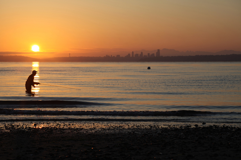 Patrick Kent strips his fly as the sun rises over the Seattle skyline